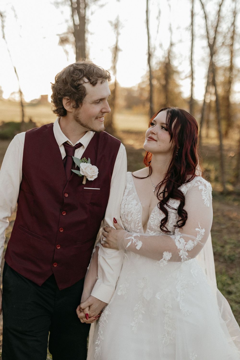 Couple shares joyful moment in formal wedding attire against autumn backdrop.