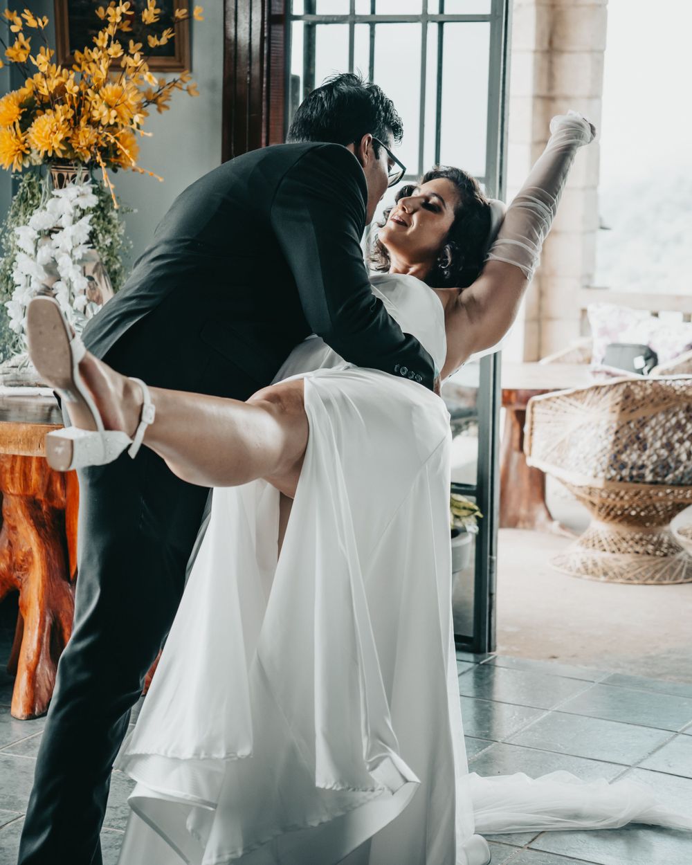 A couple performs a romantic dance dip pose in elegant wedding attire.