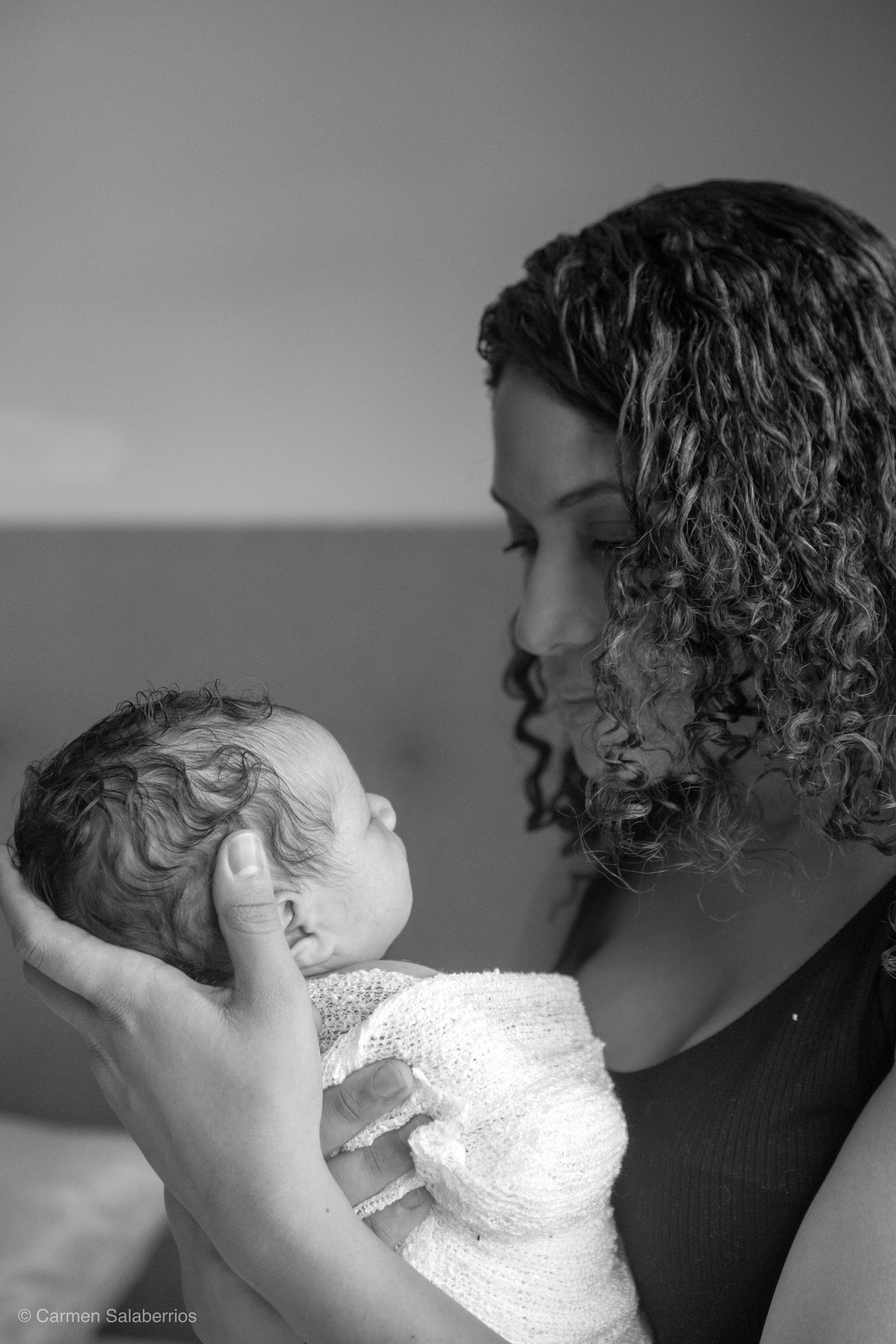 Tender black and white portrait of mother holding newborn close to her face.