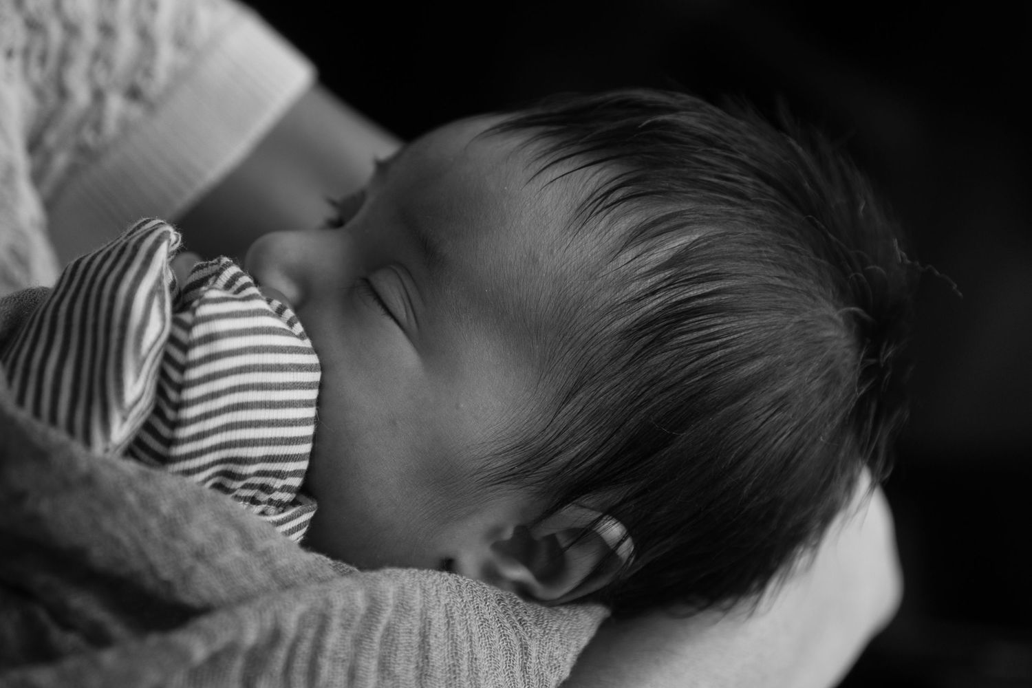 Black and white side profile of sleeping infant in striped clothing.