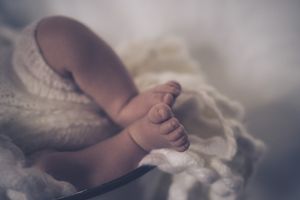 Close-up of tiny baby feet resting on delicate lace fabric.