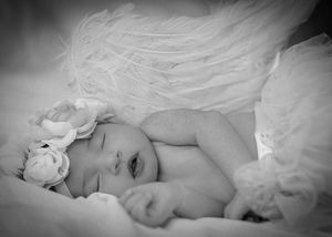 Black and white portrait of sleeping baby with white floral accessory.