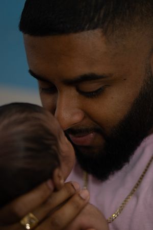 A close-up portrait of a bearded parent sharing an intimate moment with their infant child.