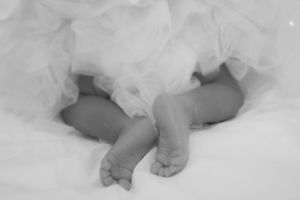 Tiny feet peeking out from layers of white tulle fabric.