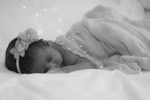 Black and white image of sleeping newborn in delicate lace dress.