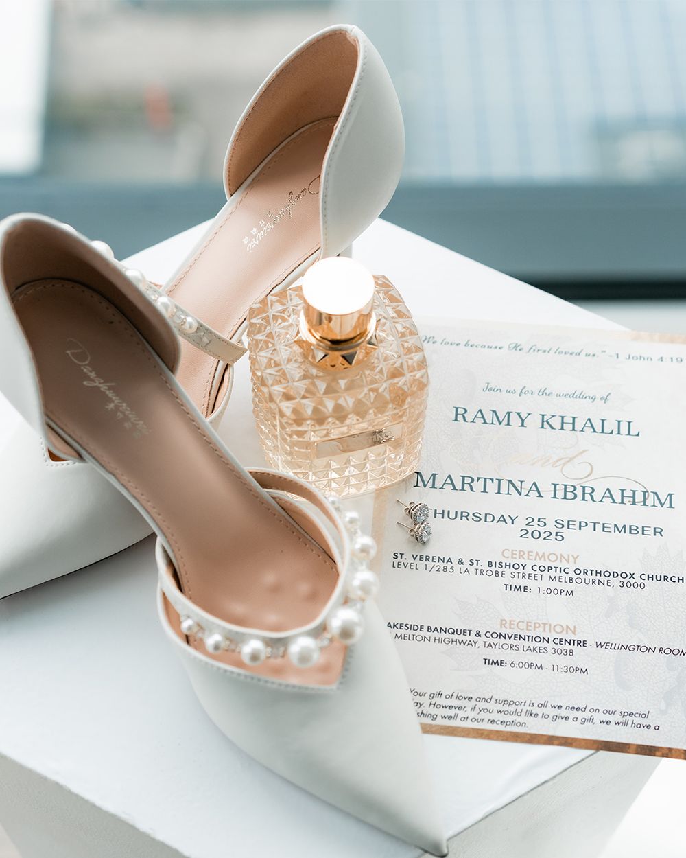 Wedding invitations and elegant bridal shoes with crystal details arranged on a light surface.