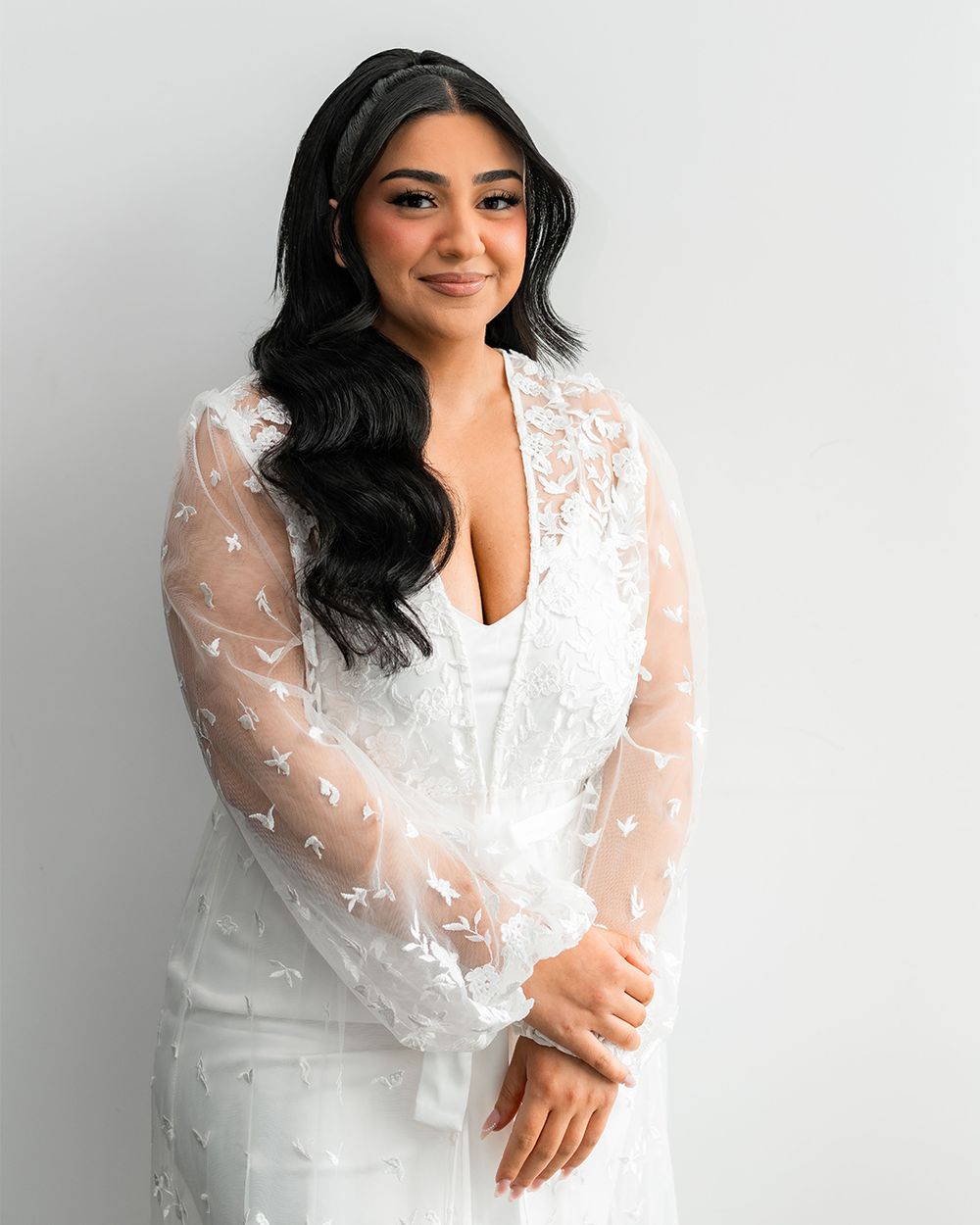 A romantic bridal portrait showcasing a sheer lace overlay and elegant white wedding gown.