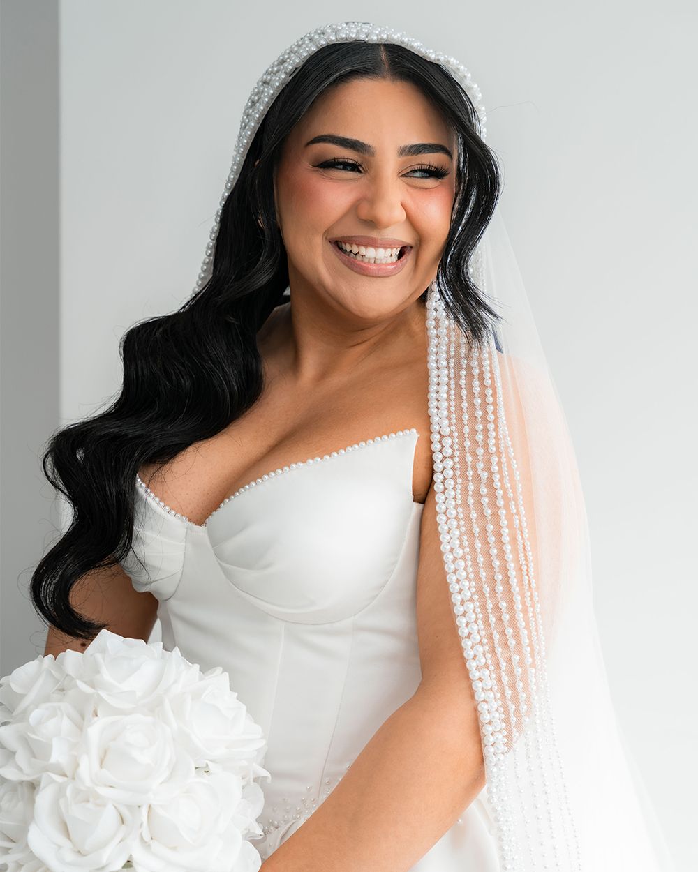 A joyful bridal portrait featuring a sparkling crystal veil and classic white wedding dress.