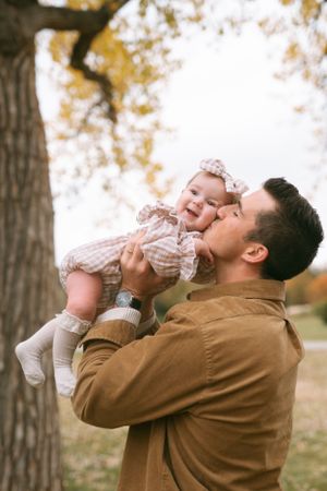 Playful father-child moments captured in autumn park setting with golden trees.