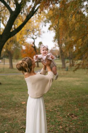 Joyful outdoor photoshoot in autumn featuring a white dress against fall foliage.