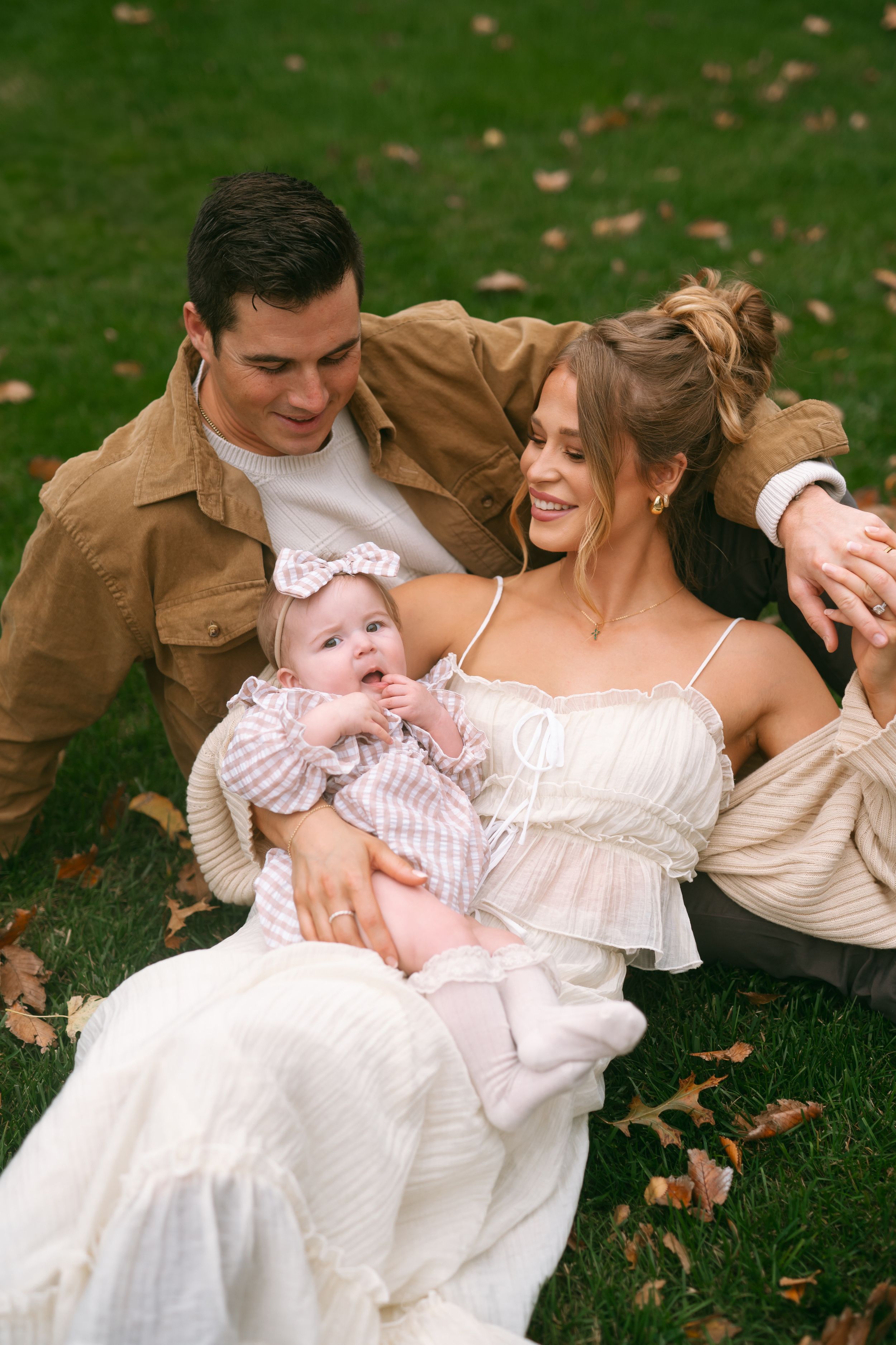 Intimate family portrait session on grass with autumn leaves.