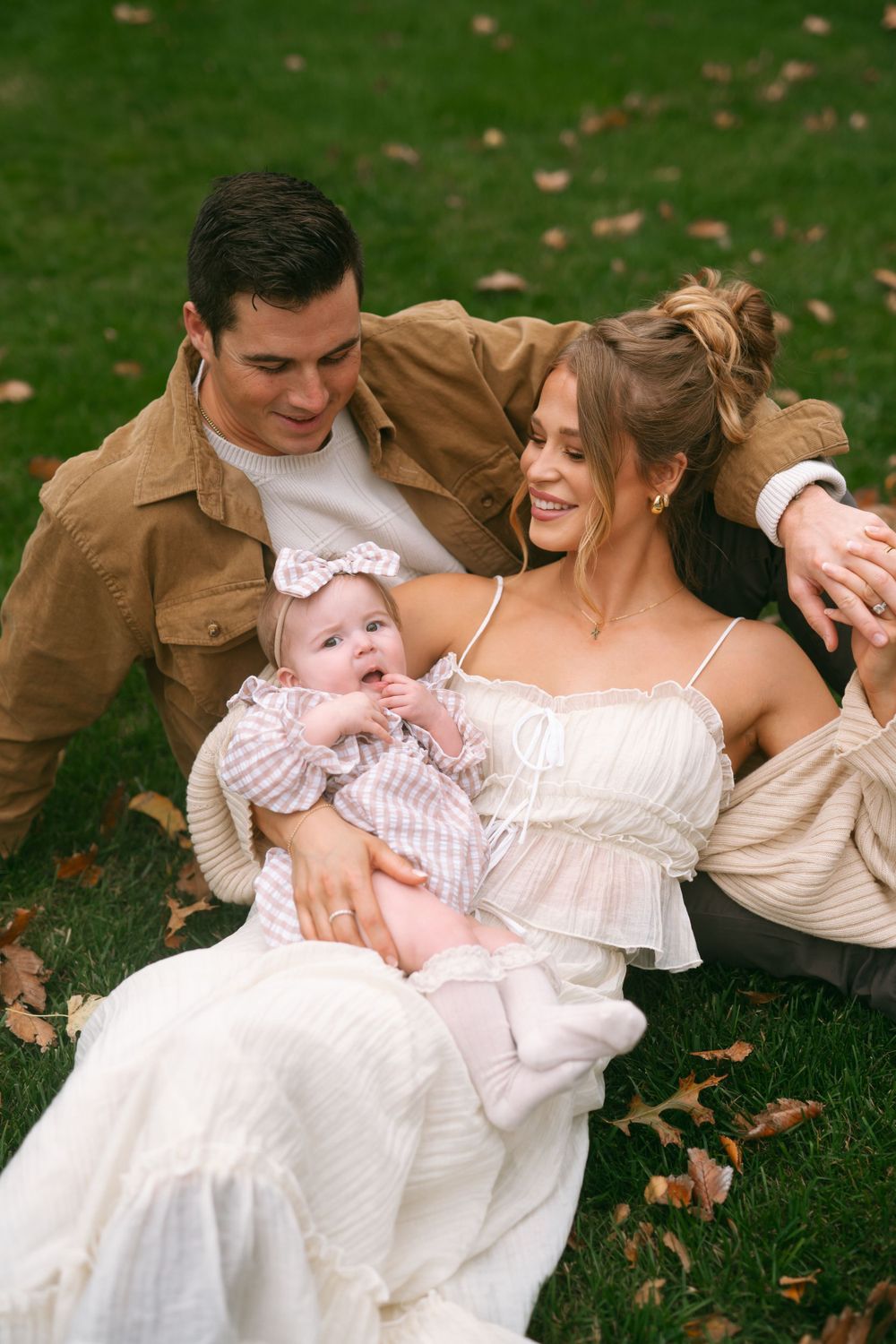 Intimate family portrait session on grass with autumn leaves.