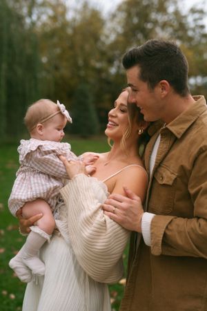 Candid family moments captured outdoors with parents and baby in autumn setting.