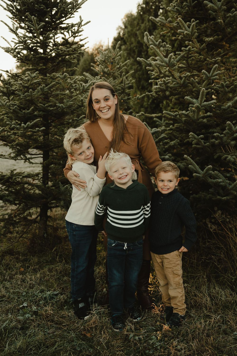 A joyful group portrait among evergreen trees during golden hour.