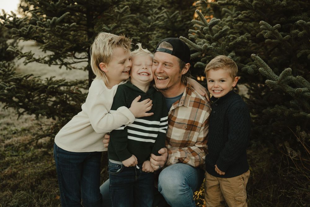 A heartwarming family moment captured among pine trees during sunset.
