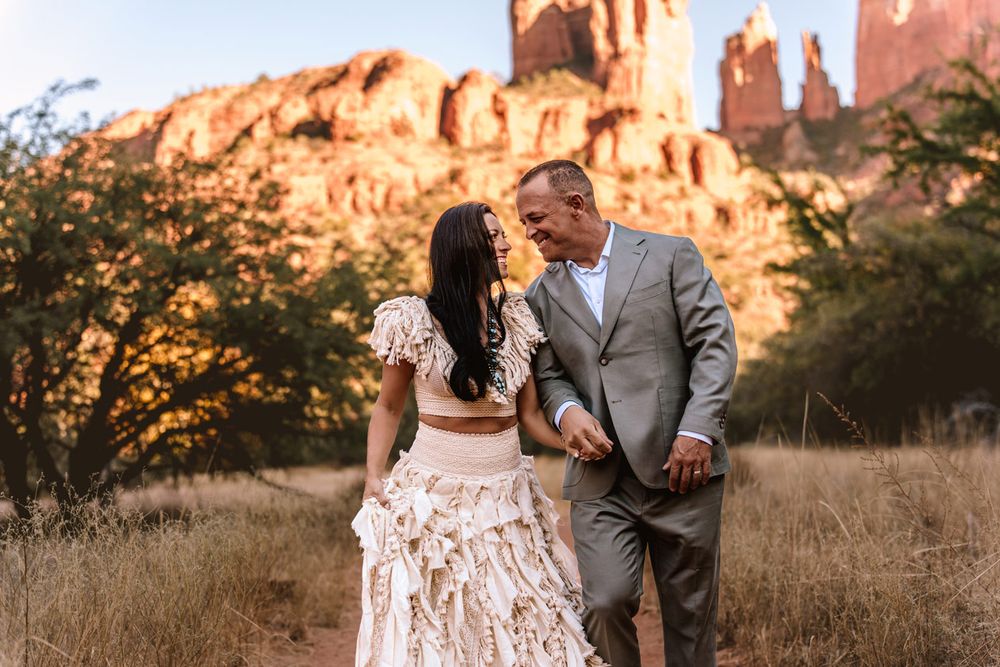 A couple shares an intimate moment on a desert trail with stunning Sedona red rock formations in the background.