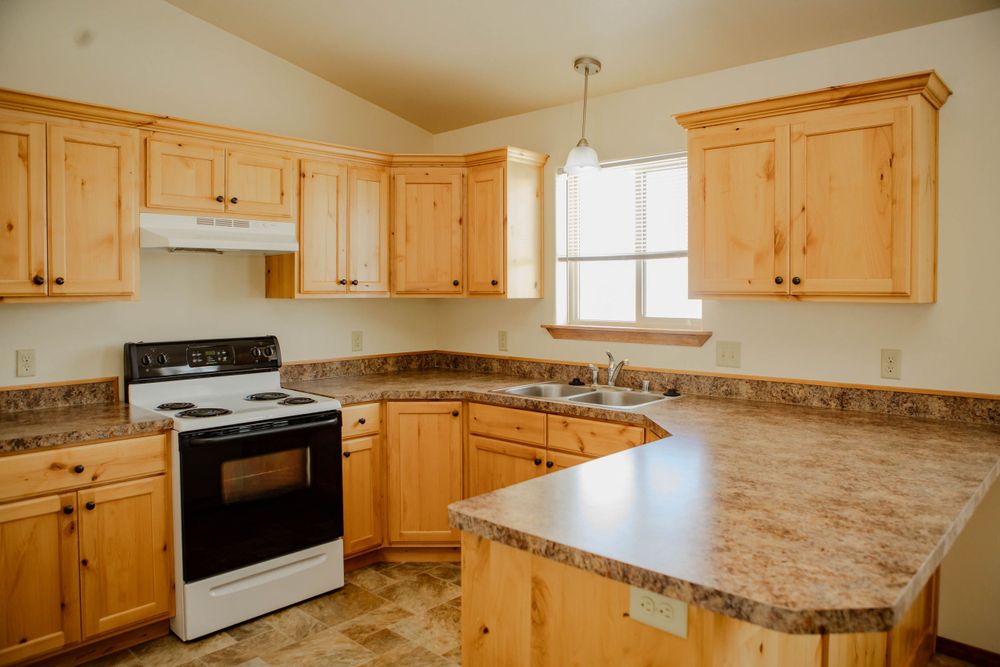 Light wood kitchen cabinets with granite countertops and peninsula in modern home interior.