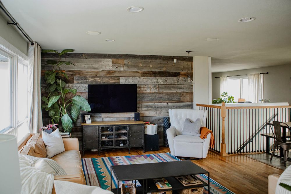 Modern living room with reclaimed wood accent wall, wall-mounted TV, white furniture and hardwood floors.