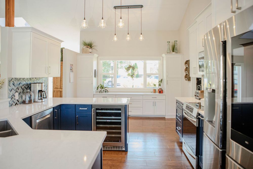 Modern kitchen with navy blue cabinets, white countertops, pendant lighting and stainless steel appliances.