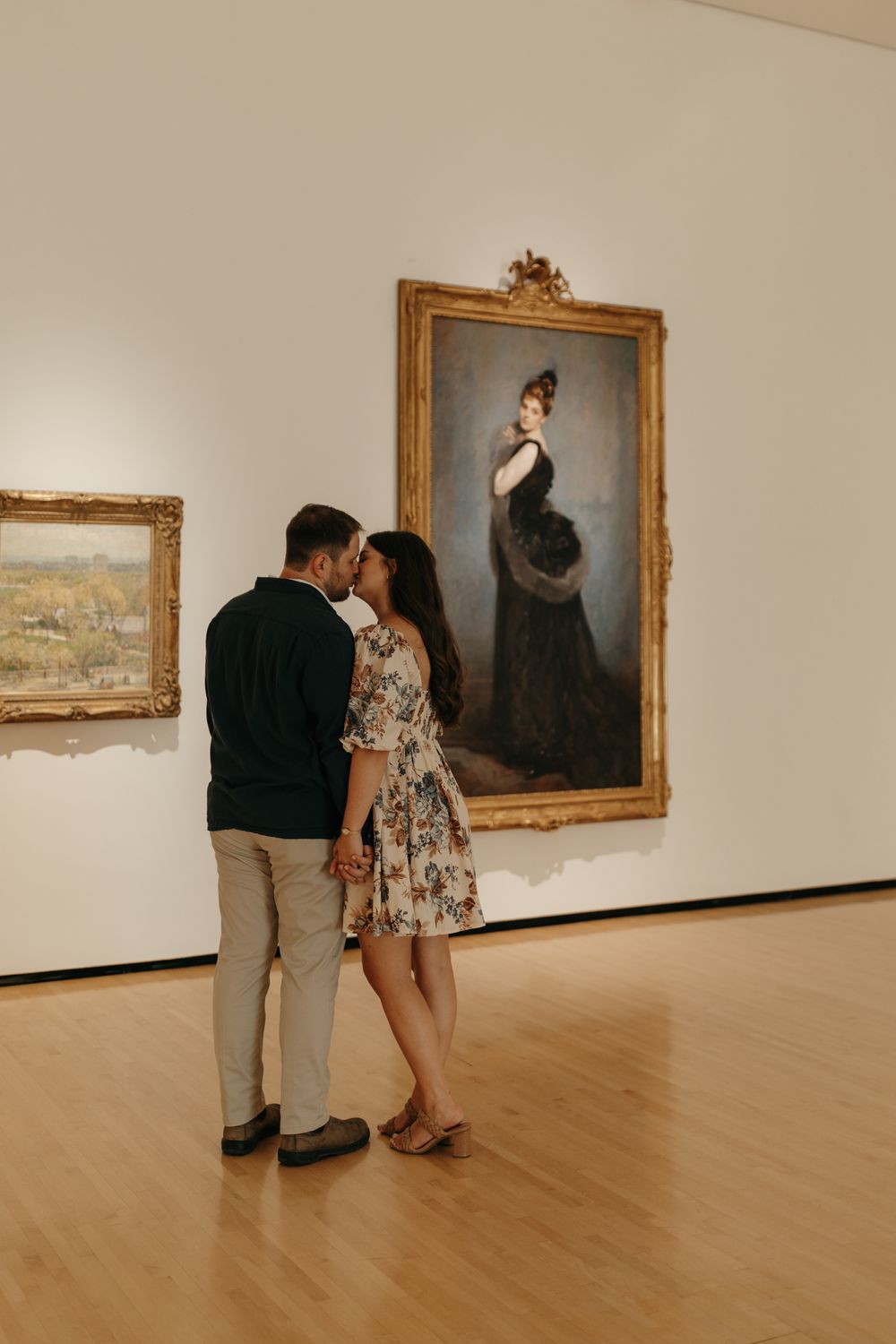 A romantic couple views a classical portrait painting in an elegant museum gallery.