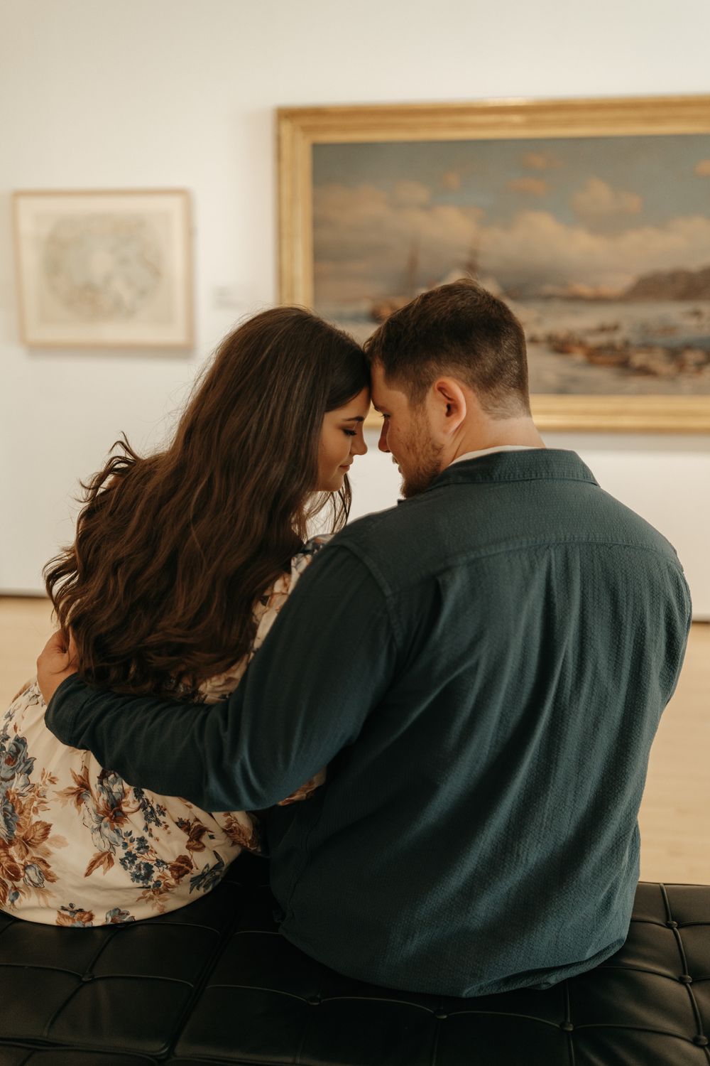 A romantic moment shared between two people viewing artwork in a gallery.