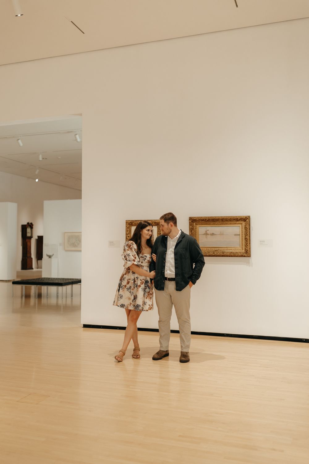 A couple shares a tender moment while viewing art in a modern museum gallery.