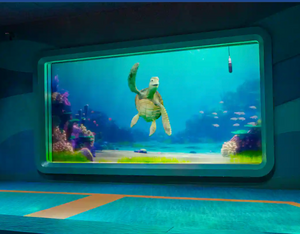 Aquarium interior exhibits featuring large viewing windows illuminated in blue lighting with fish and coral displays.