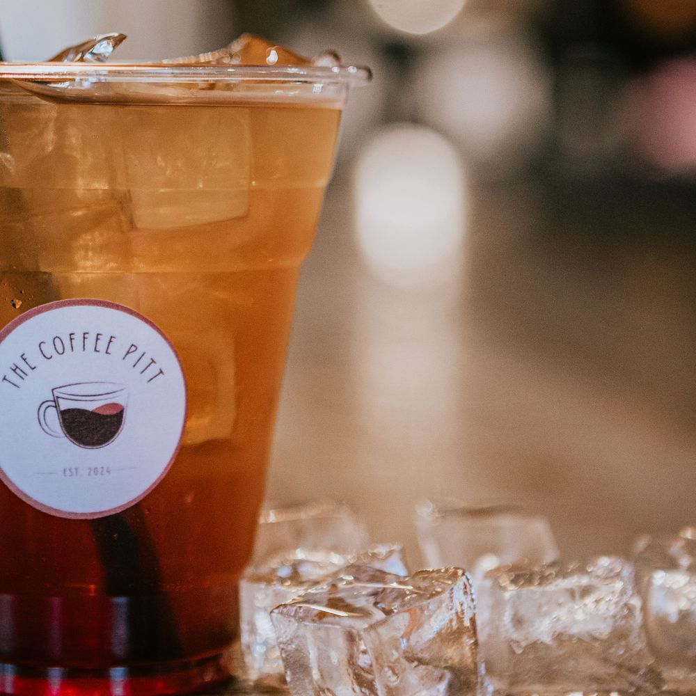Iced coffee drink in plastic cup with coffee shop logo and ice cubes.