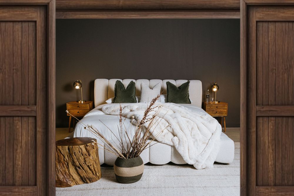 Modern bedroom featuring wooden panels, white bedding, and natural decor elements in an earthy color scheme.