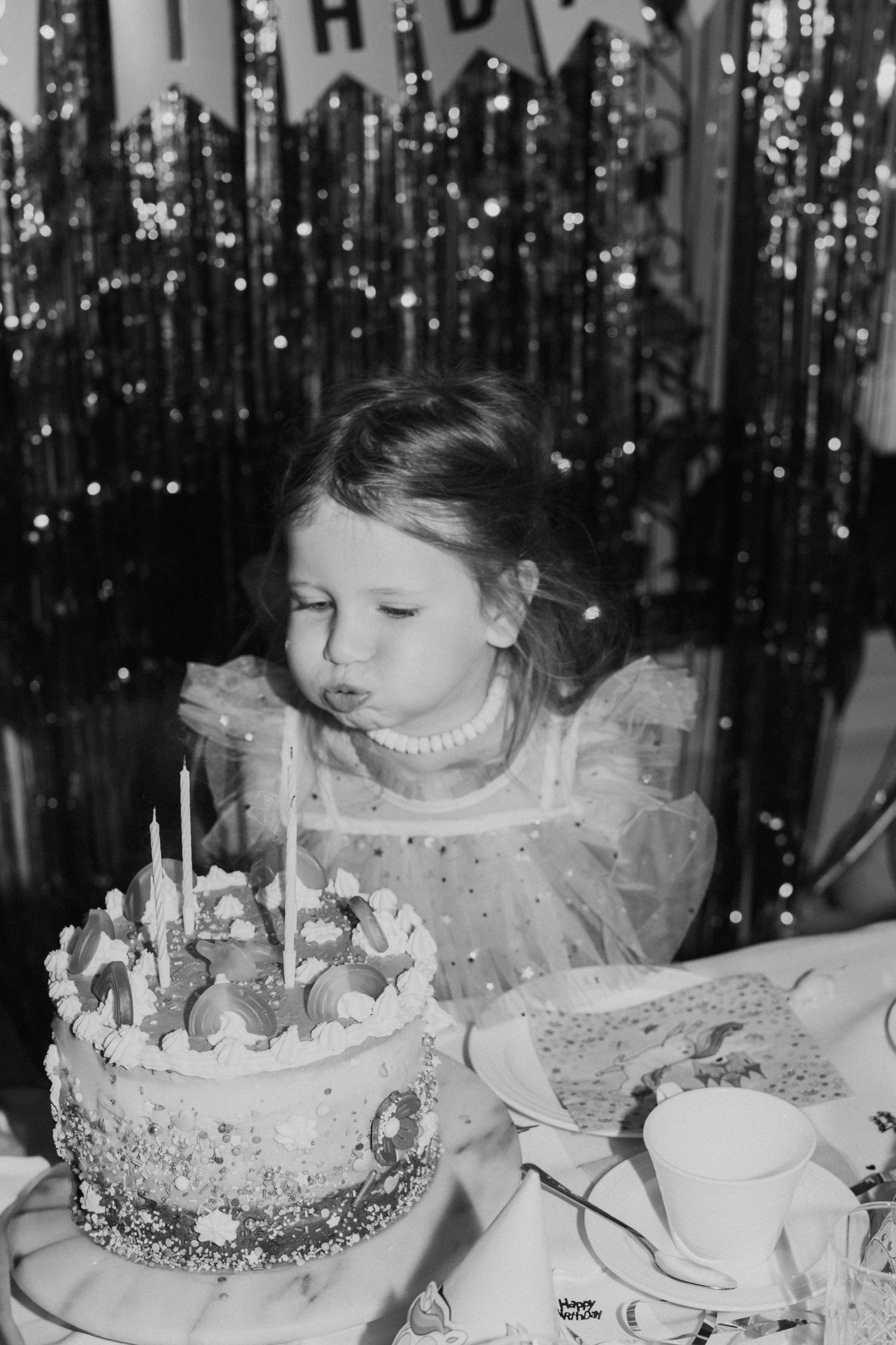 Black and white photo of a birthday celebration with a decorated cake and sparkling background.