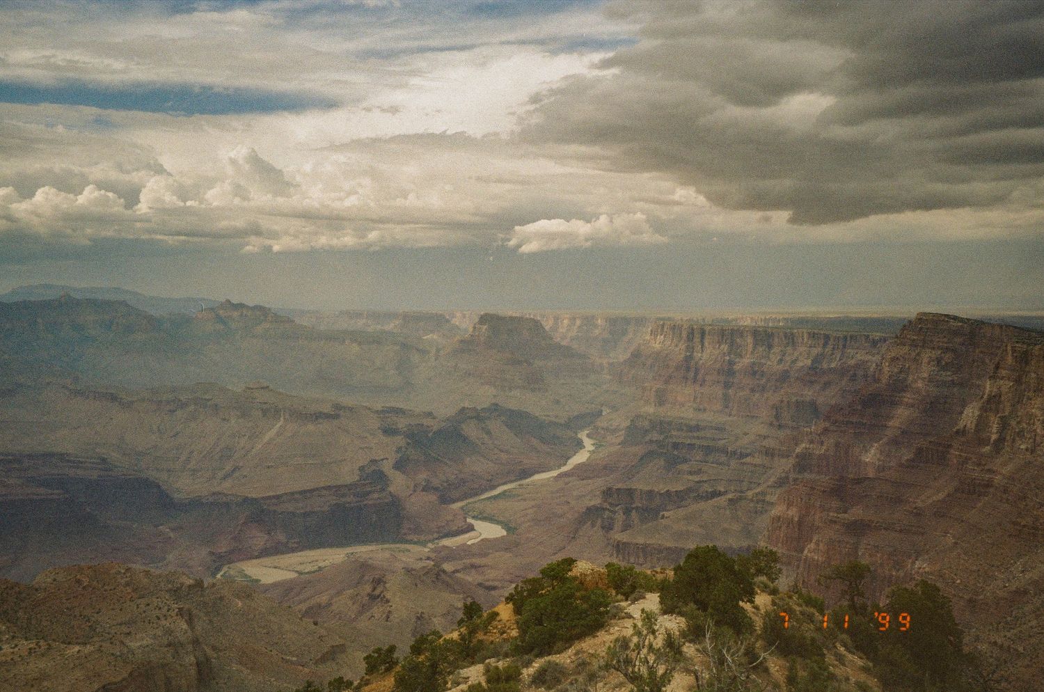 Panoramic vista of the Grand Canyon with winding river visible in the distance.