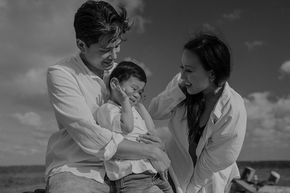 Parents embracing their child during pregnancy session Riviera Maya.