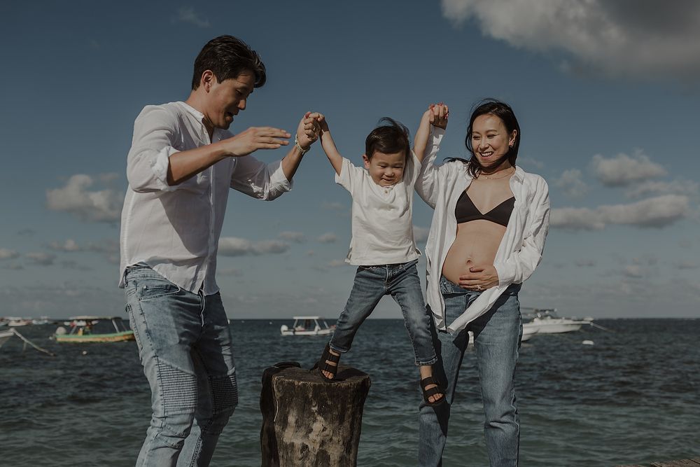 Playful maternity portraits with father lifting child in Puerto Morelos.