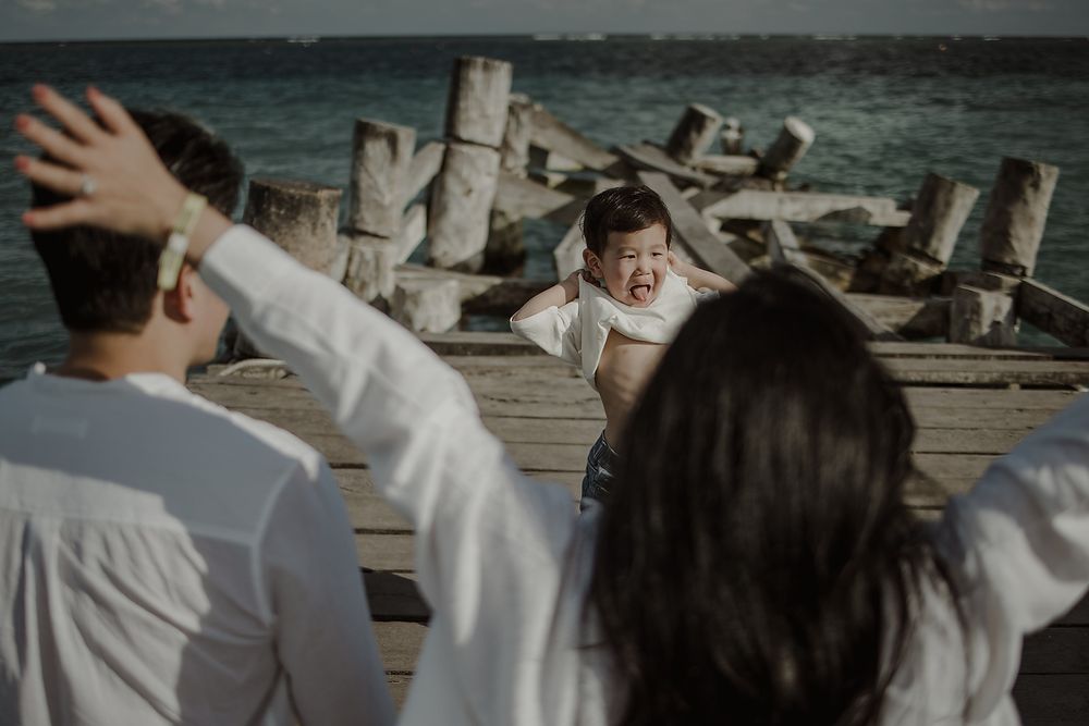 Child looking at mother’s baby bump during pregnancy photoshoot.