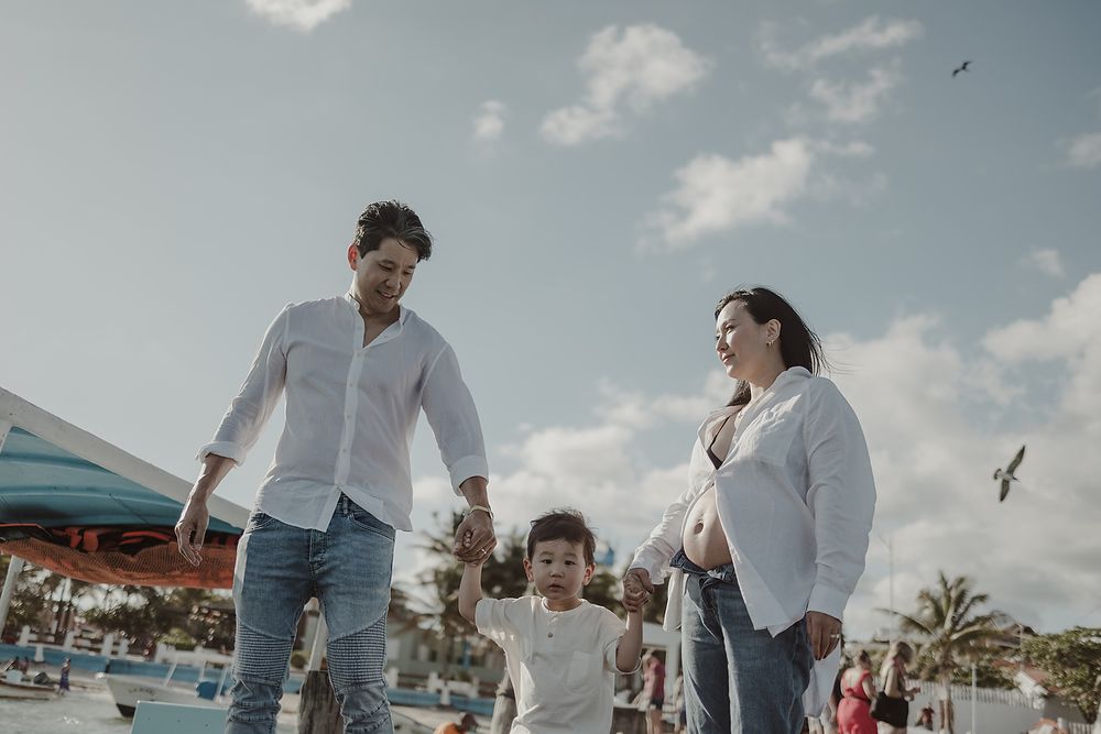 Joyful walk on Puerto Morelos pier during family maternity photoshoot.