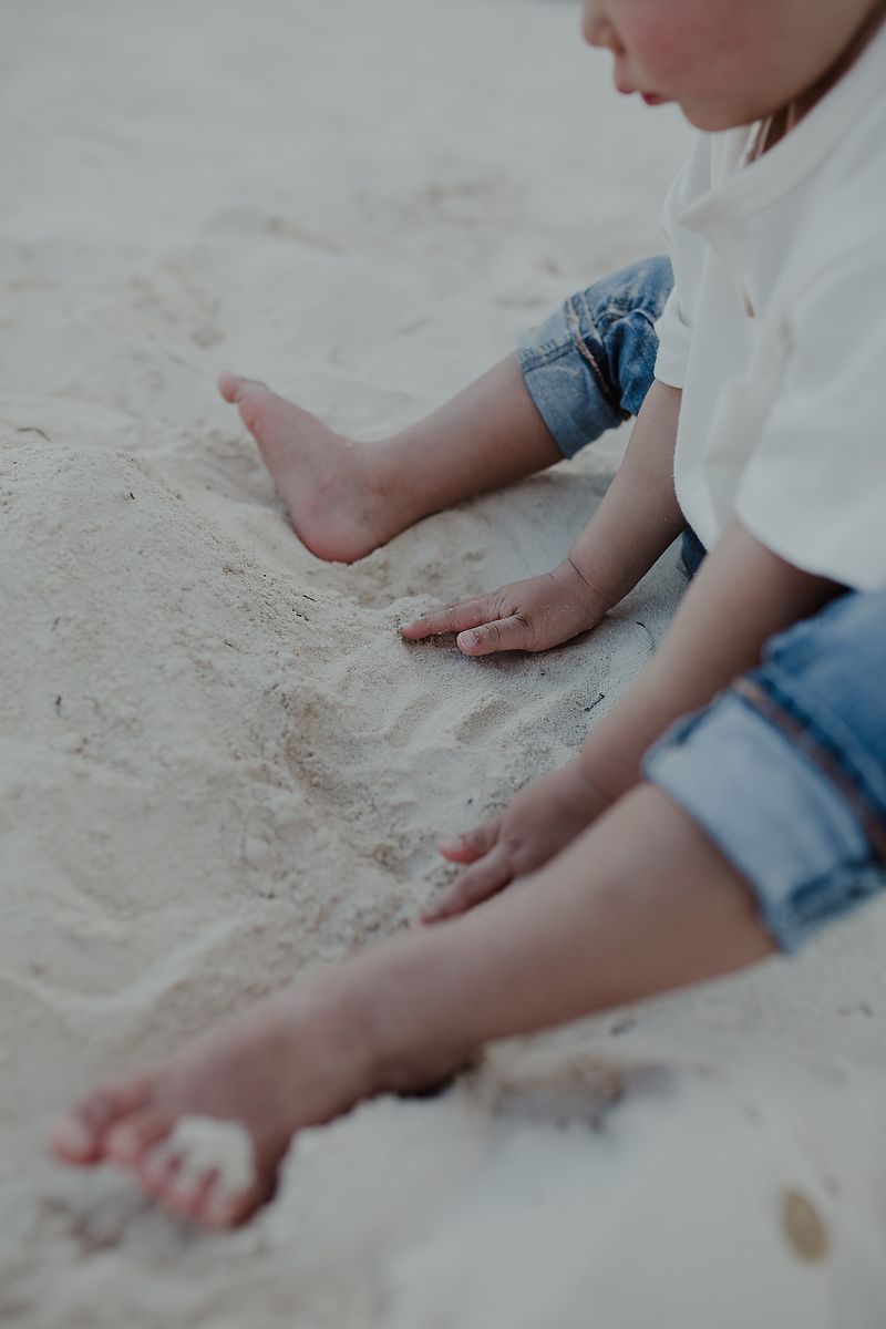 Close-up detail of child’s feet in the sand during family session in Puerto Morelos beach.