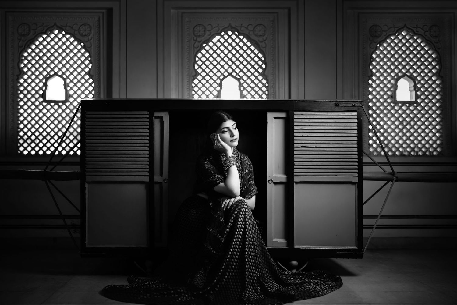 Black and white portrait in an elegant architectural setting with arched windows.