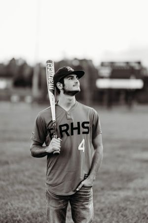 Black and white photo of RRHS #4 baseball player holding a Marucci bat on a field.