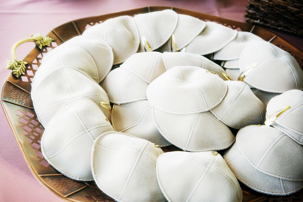 Close-up detail photograph of a grouping of white suede kippah or yamaka.