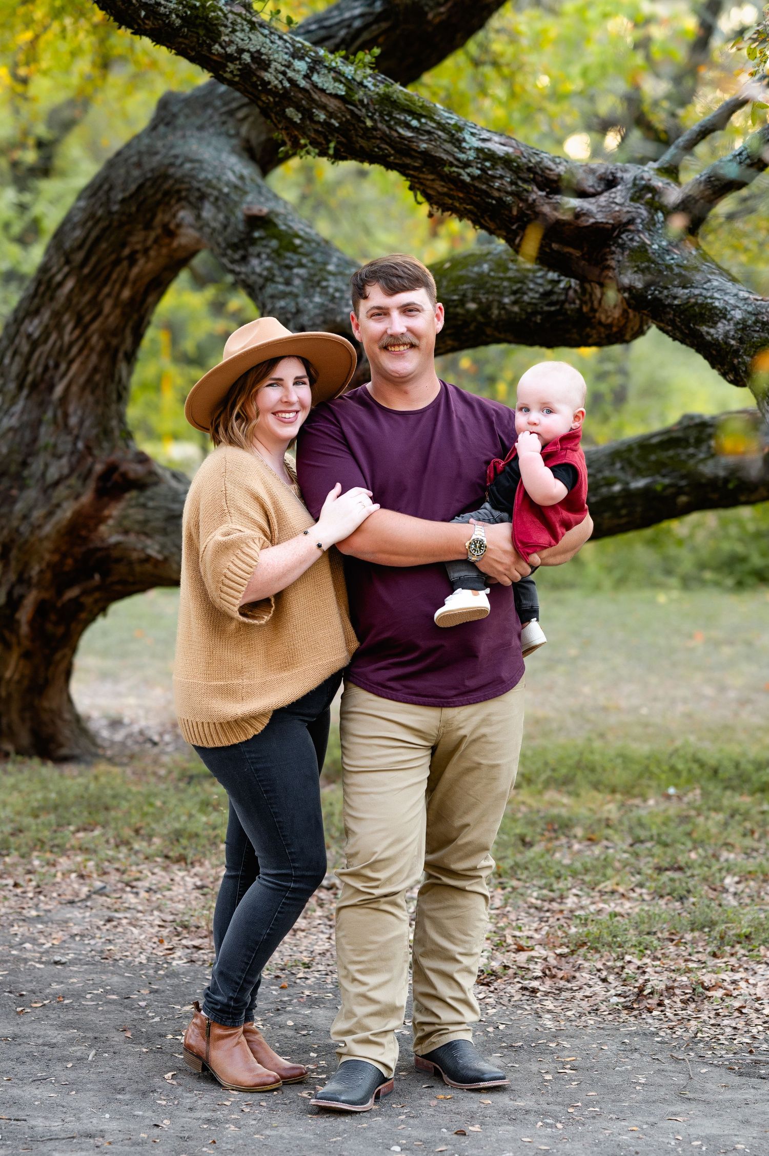 couple poses with infant son in front of a tree during mesquite, tx fall family mini photo session by dallas family and newborn photographer