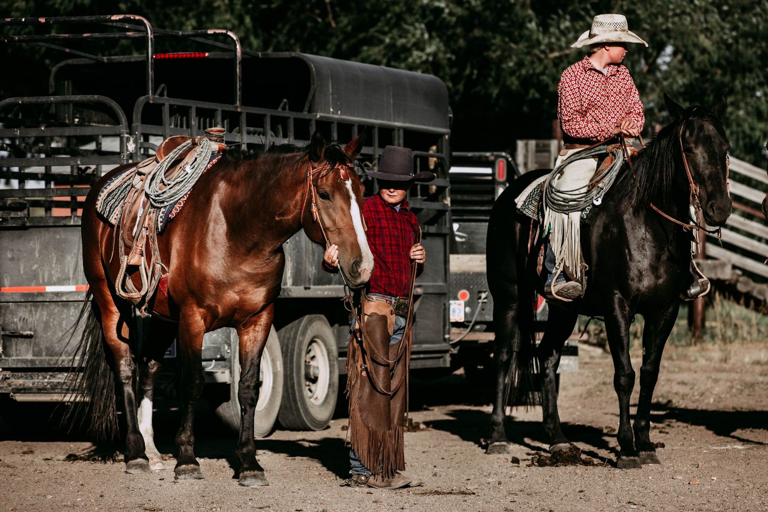 horses and young cowboys waiting in rustic ranch setting.