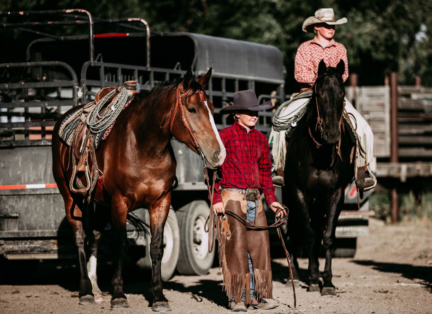 Western horses and riders gathered near trailers and ranch equipment.