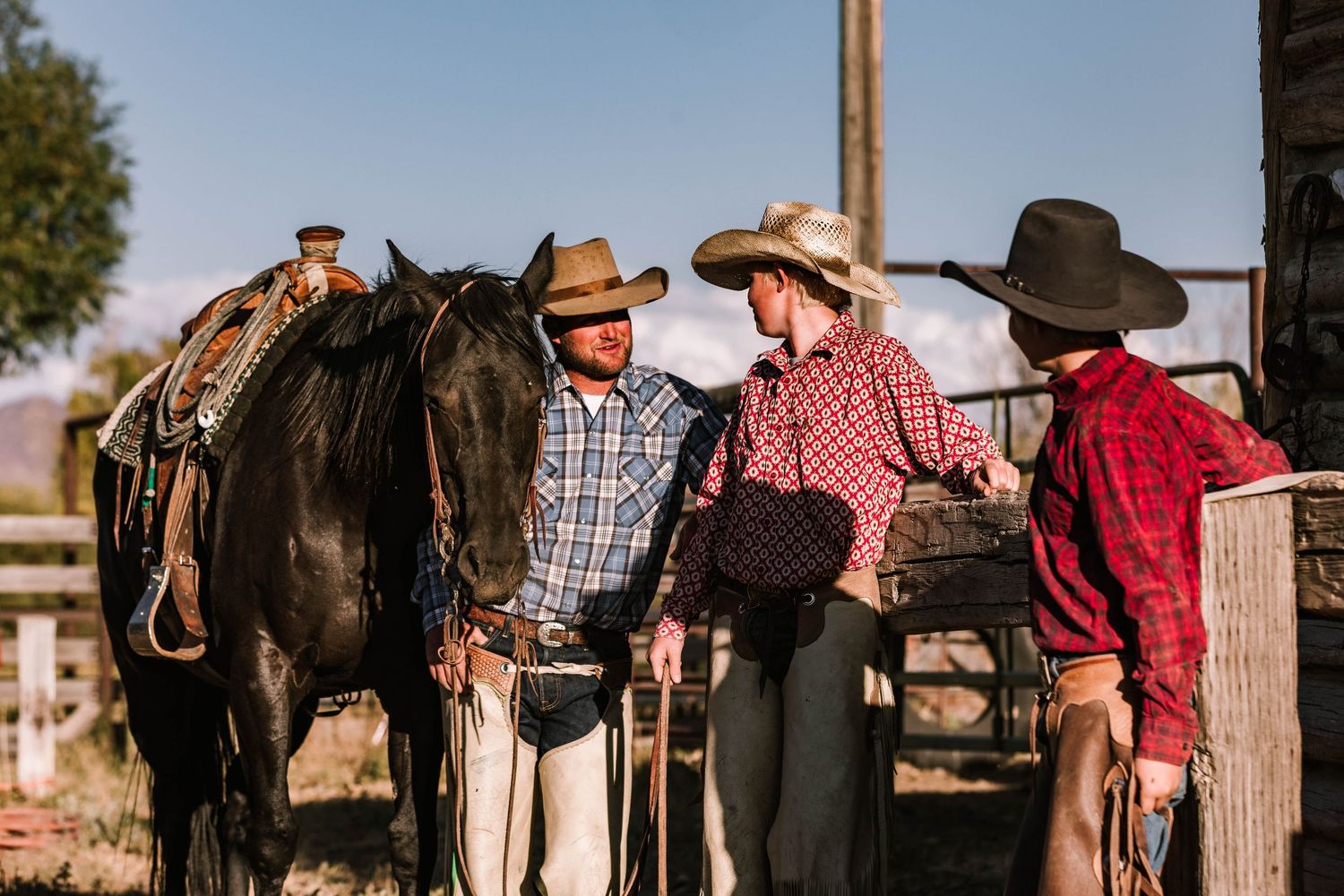 Cowboys, father and sons, around a dark horse at a Nevada ranch.