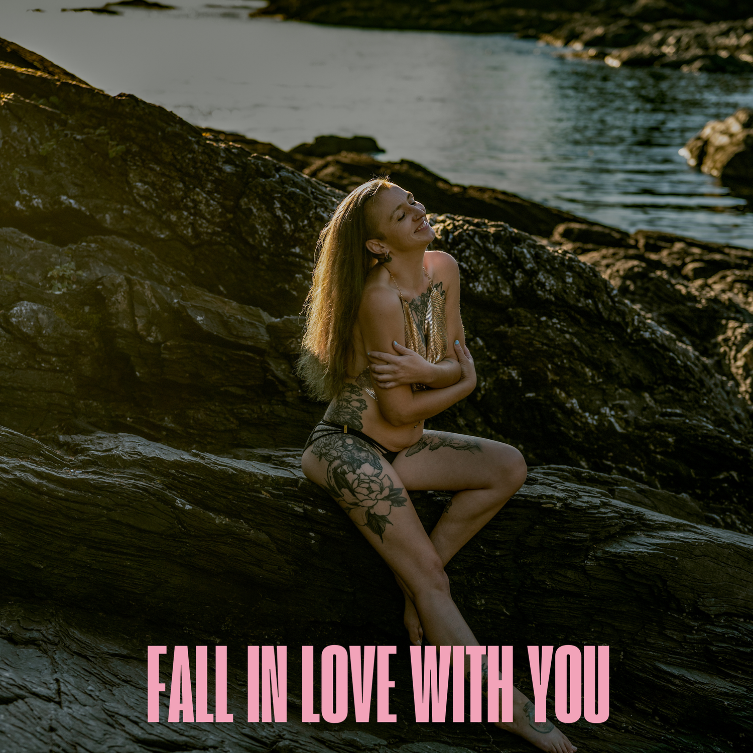 Artistic sunset photo on rocky beach with overlaid pink text saying Fall in Love with You.