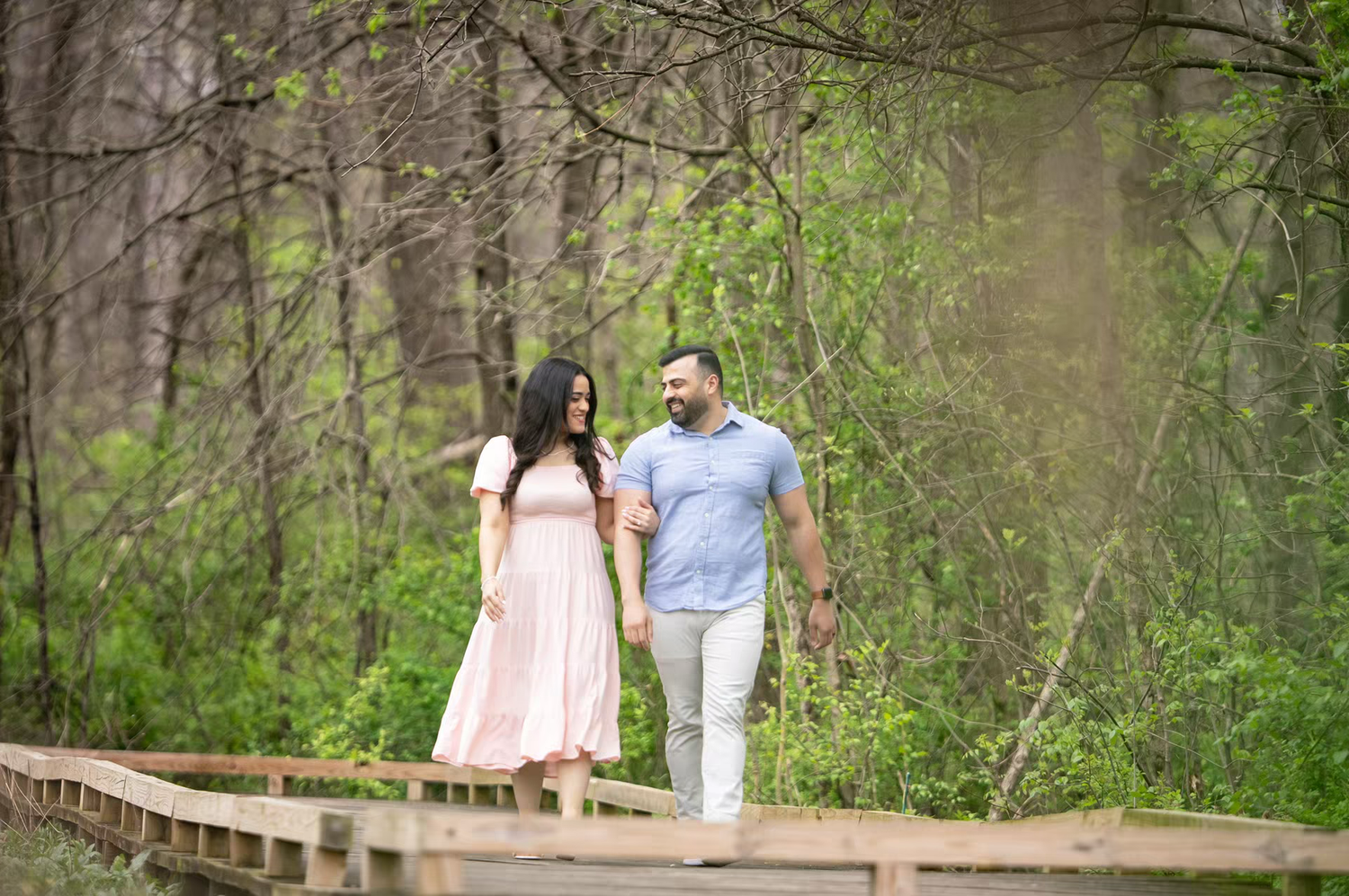 engagement photo of Couple holding hands walking on wooden boardwalk path at Inniswood Metro Gardens