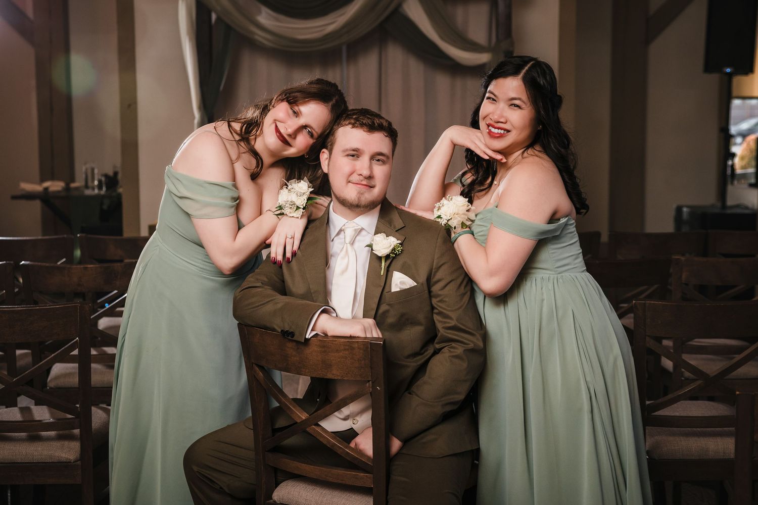 Wedding party portrait at Briar Barn Inn ceremony space with groom seated and bridesmaids posing on either side in sage green dresses