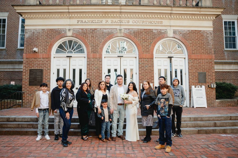Family group photo outside Franklin D. Reiche Courthouse brick building after a wedding ceremony.