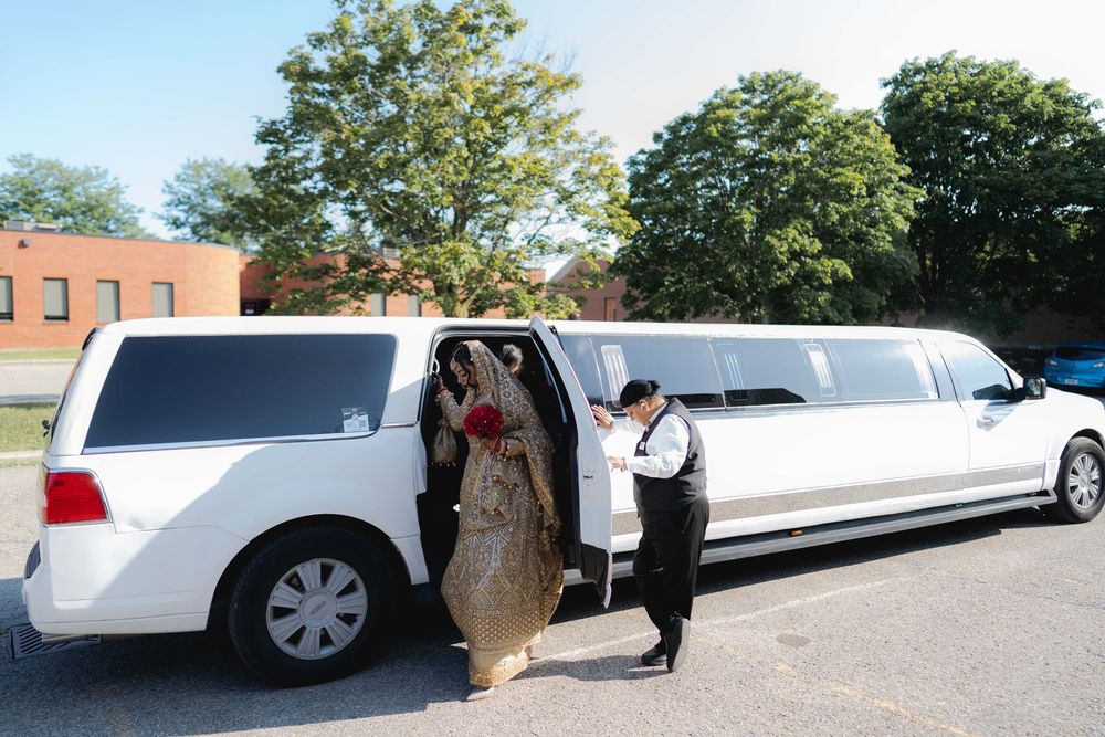 Bride in gold lehenga entering white stretch limousine with chauffeur assistance outdoors.
