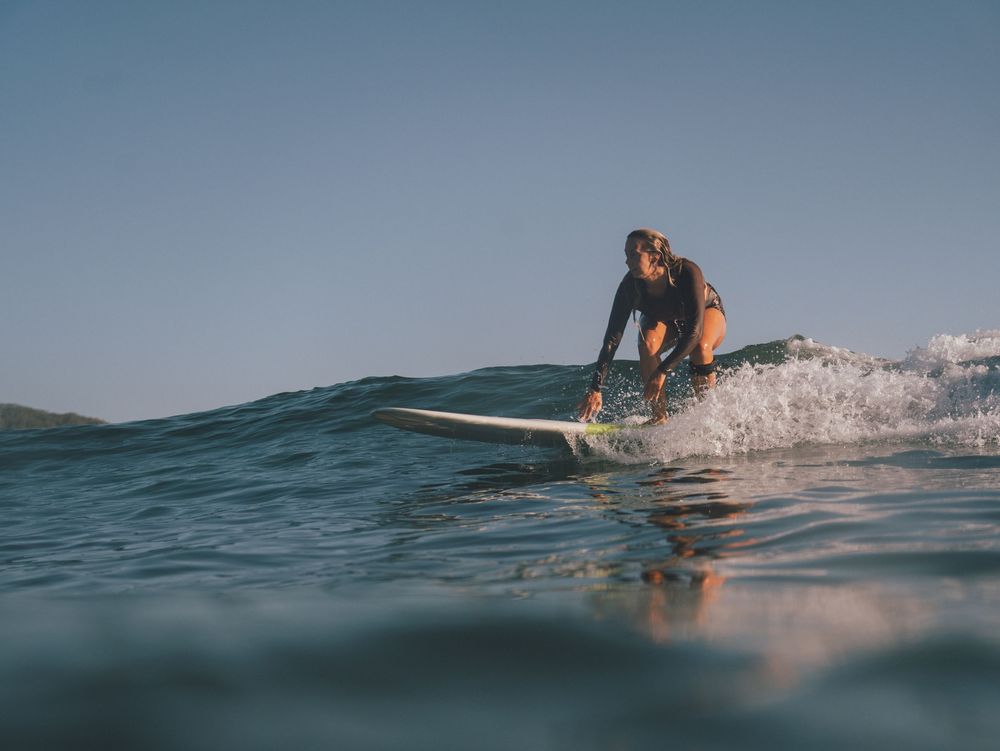 woman surfer taking off on a wave at Seal Rocks near Newcastle NSW