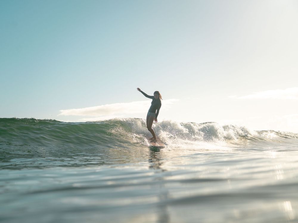 woman and reflection of longboard surfing in morning light at Seal Rocks near Newcastle NSW